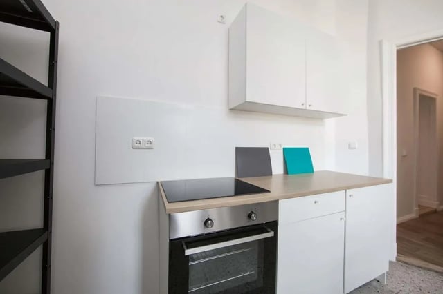 Modern white cabinets oven stove and shelving kitchen at Hohenzollerndamm 53.6 in Berlin Student Accommodation