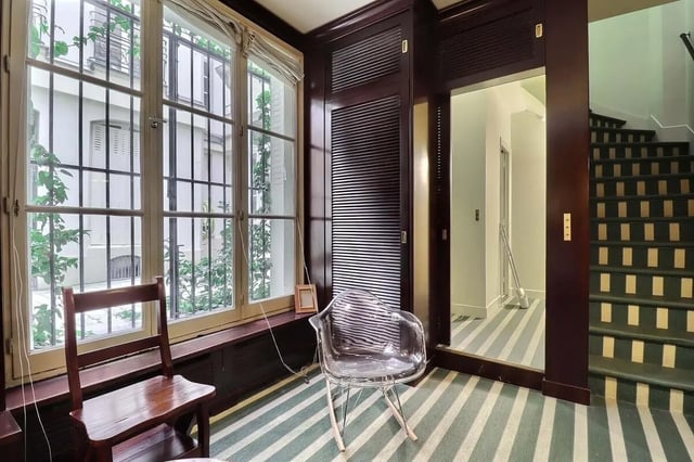 Chairs by barred window next to striped stairs Living room at Apartment in Rue Saint-Honoré, 75001 Paris, France in Paris Student Accommodation