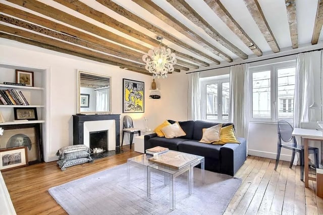Dark sofa with yellow pillows fireplace and beams living room at Apartment 1 bedroom 60m² in Paris Student Accommodation