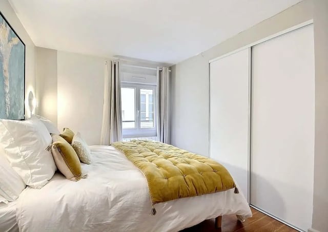 Bed with white linens yellow throw and closet bedroom at Apartment 1 bedroom 60m² in Paris Student Accommodation