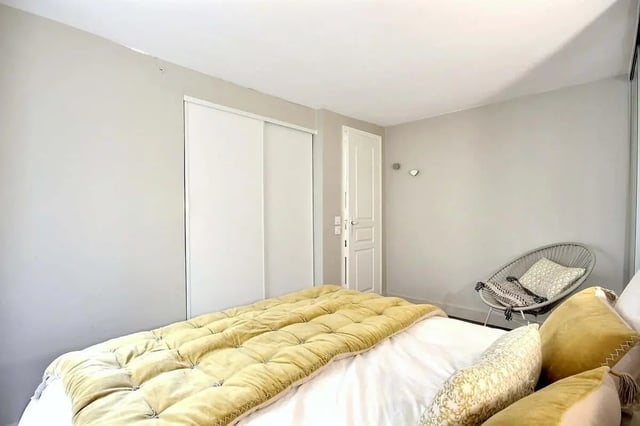 Bed with yellow spread white linens grey chair Bedroom at Apartment 1 bedroom 60m² in Paris Student Accommodation