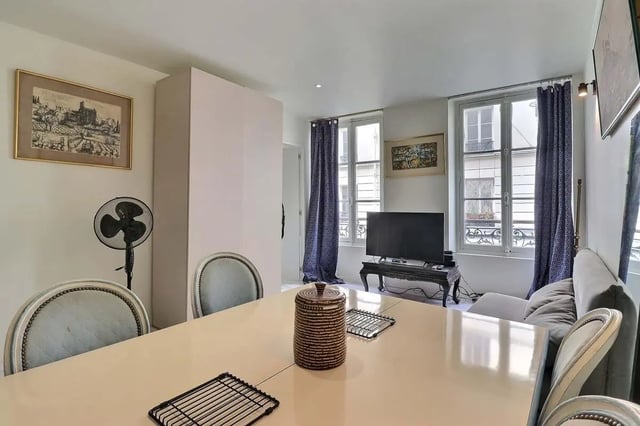 Table fan framed art closet chairs couch and television living room at Apartment in Rue Sedaine, Paris for 37 m² with 1 bedroom in Paris Student Accommodation