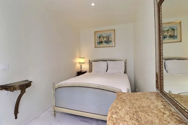 Bed with white linens nightstand lamp painting and mirror bedroom at Apartment in Rue Sedaine, Paris for 37 m² with 1 bedroom in Paris Student Accommodation