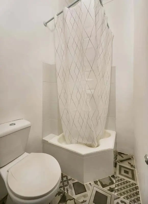 Toilet and bathtub with patterned shower curtain bathroom at Casa Abel II – Room 5 in Lisbon Student Accommodation