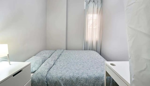 Bed with patterned duvet desk and lamp bedroom at Casa Abel II – Room 5 in Lisbon Student Accommodation