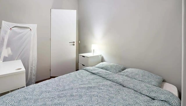 Bed with patterned duvet nightstand lamp and door bedroom at Casa Abel II – Room 5 in Lisbon Student Accommodation