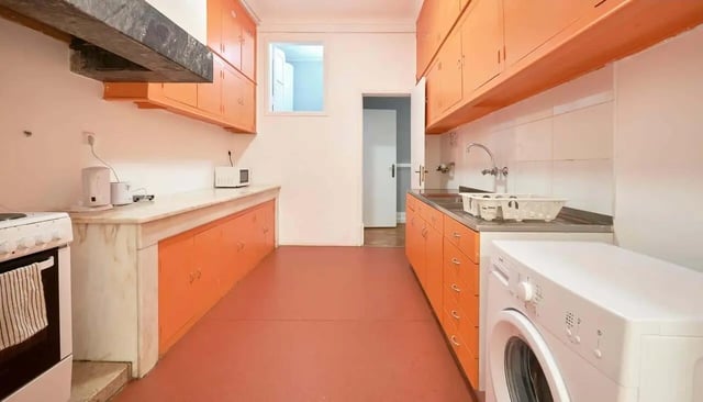 Orange cabinets stove sink and washing machine kitchen at Casa Elias III – Room 11 in Lisbon Student Accommodation