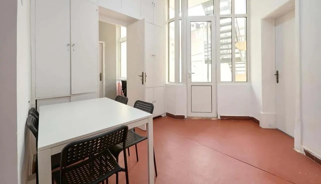 White table black chairs built-in cabinets and doors living room at Casa Elias III – Room 11 in Lisbon Student Accommodation
