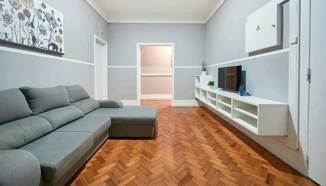 Grey sectional couch with artwork and TV living room at Casa Elias III – Room 11 in Lisbon Student Accommodation