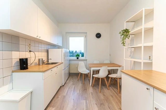 White cabinets refrigerator sink chairs table bookshelf kitchen at Sterndamm 75.2 75.3 in Berlin Student Accommodation