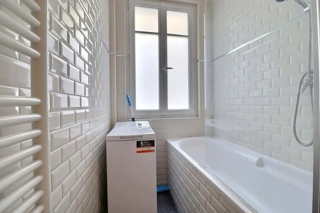 Washing machine bathtub window white tiled bathroom at Apartment in Rue Etienne Jodelle, 75018 Paris, France in Paris Student Accommodation