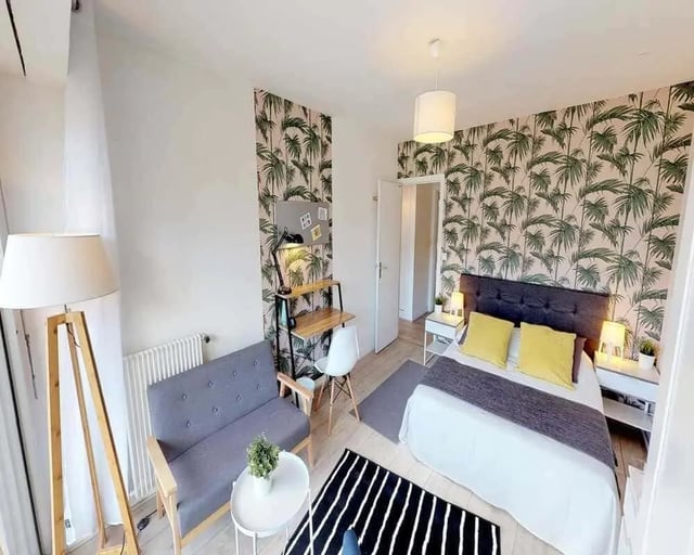 Bed with yellow pillows desk and sofa bedroom at Chambre dans le rue d'Hautpoul in Paris Student Accommodation