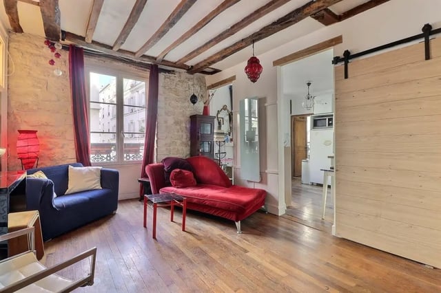 Blue sofa red chaise wood beams open kitchen living room at Apartment 2 bedrooms 63m² in Paris Student Accommodation