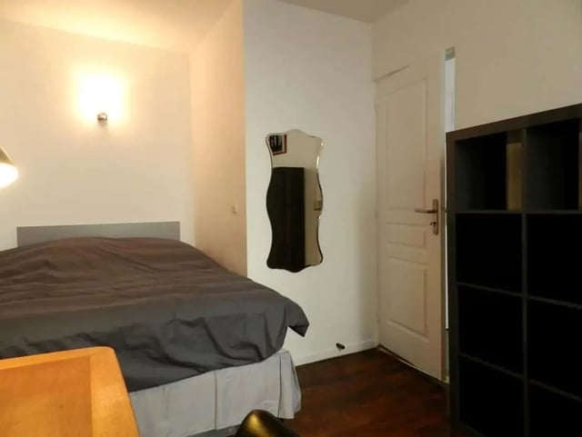Bed with dark covers white door black shelf bedroom at Apartment 1 bedroom 28m² in Paris Student Accommodation