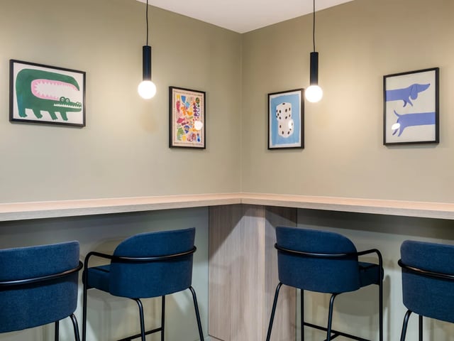 Four blue chairs at counter with wall art communal area at Dunaskin Mill in Glasgow Student Accommodation