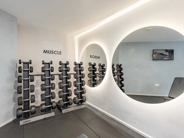 Dumbbells on racks illuminated mirror gym area at Dunaskin Mill in Glasgow Student Accommodation
