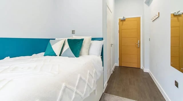 Bed with pillows near wooden door bedroom at Urban Student Village in Coventry Student Accommodation