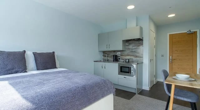 Bed with grey pillows small kitchen area and dining area at Urban Student Village in Coventry Student Accommodation