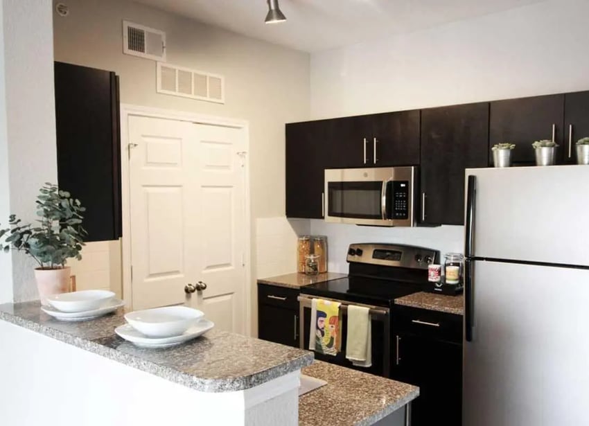 White plates on counter with stainless steel appliances and refrigerator kitchen at 21 Pearl in Austin Student Accommodation