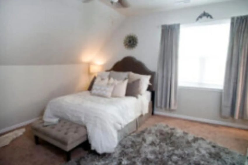 Bed with pillows blanket ottoman rug bedroom at The District at Clemson in Clemson Student Accommodation
