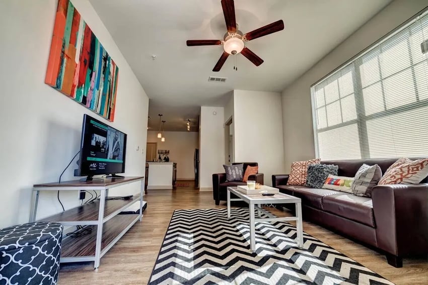 Brown leather sofa coffee table rug and TV living room at Riverfront Village in Tuscaloosa Student Accommodation