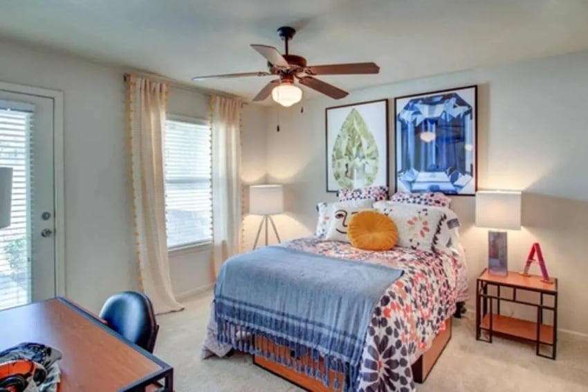 Bed artwork desk chair and ceiling fan bedroom at Gateway at Huntsville in Huntsville Student Accommodation