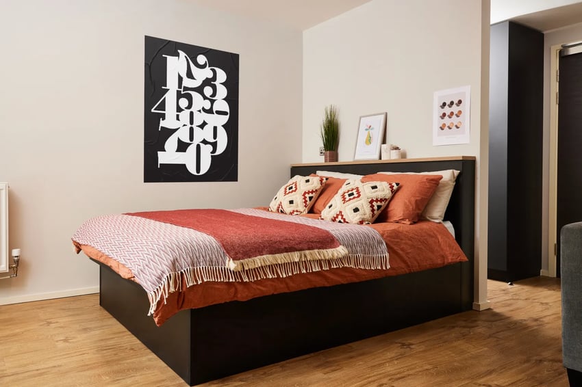 Bed with orange bedding and patterned throw Bedroom at Vita Student Pebble Mill in Birmingham Student Accommodation