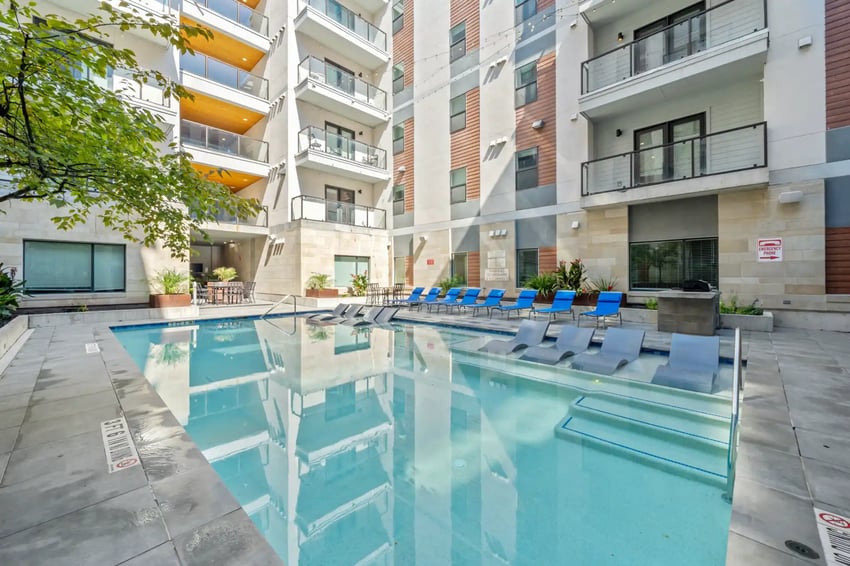 Pool with lounge chairs and building exterior. at The Villas at San Gabriel in Austin Student Accommodation
