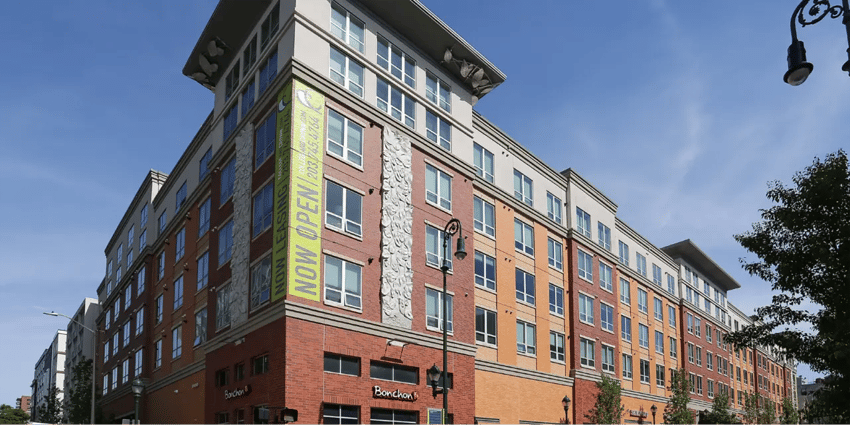 Modern building with NOW OPEN banner exterior at College and Crown Apartments in New Haven Student Accommodation