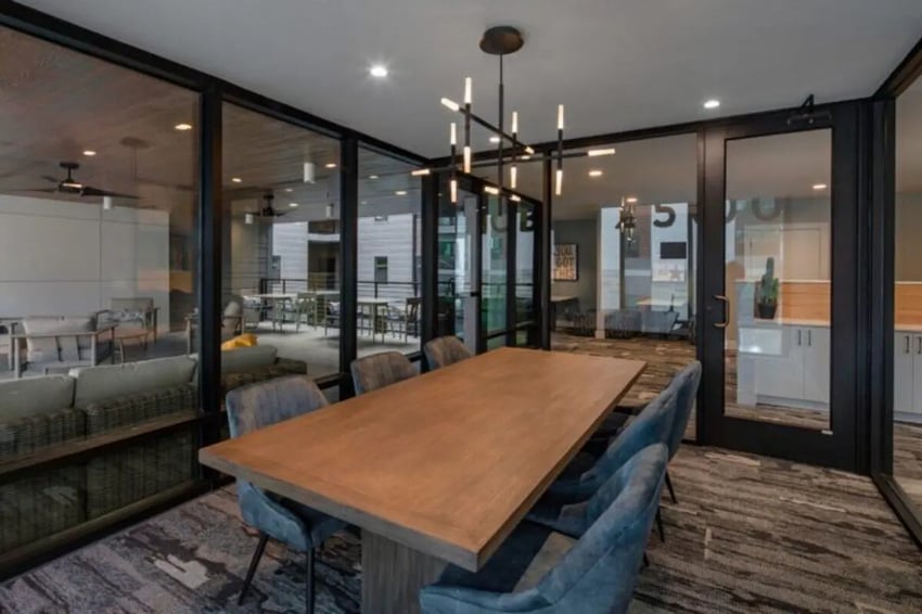 Wood table and chairs with modern chandelier common area at Noble 2500 in Austin Student Accommodation