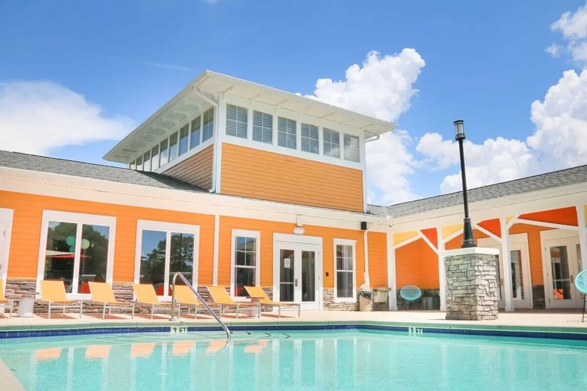 Pool with lounge chairs and orange building exterior pool area at Clemson Edge in Clemson Student Accommodation