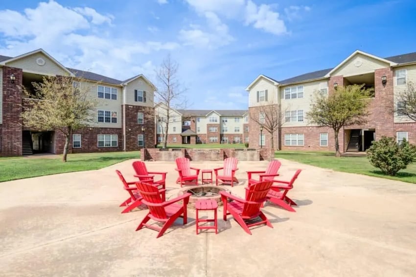 Red Adirondack chairs surrounding fire pit exterior at Mustang Village in Wichita Falls Student Accommodation