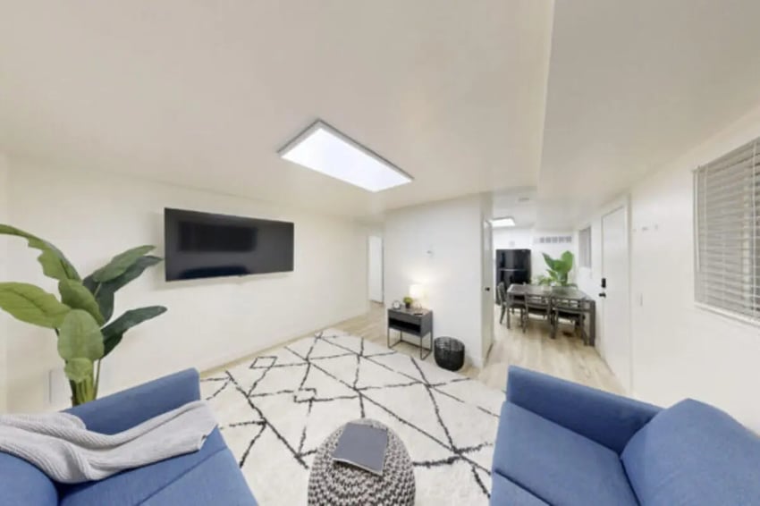 Blue sofas black TV patterned rug dining area living room at Bountiful Court Apartments in Provo Student Accommodation
