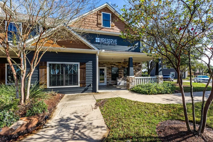 Exterior of building entrance with dark siding and stone accents at The Reserve at College Station in College Station Student Accommodation