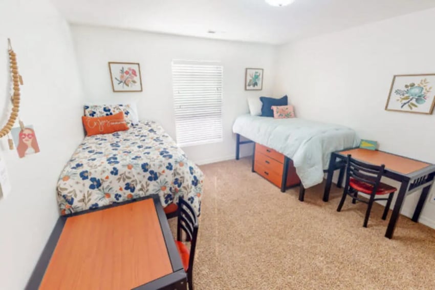Two beds desks chairs and wall art bedroom at Nauvoo House Apartments in Rexburg Student Accommodation