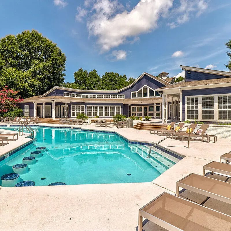 Blue building poolside with lounge chairs exterior at Muinzer Management in West Lafayette Student Accommodation