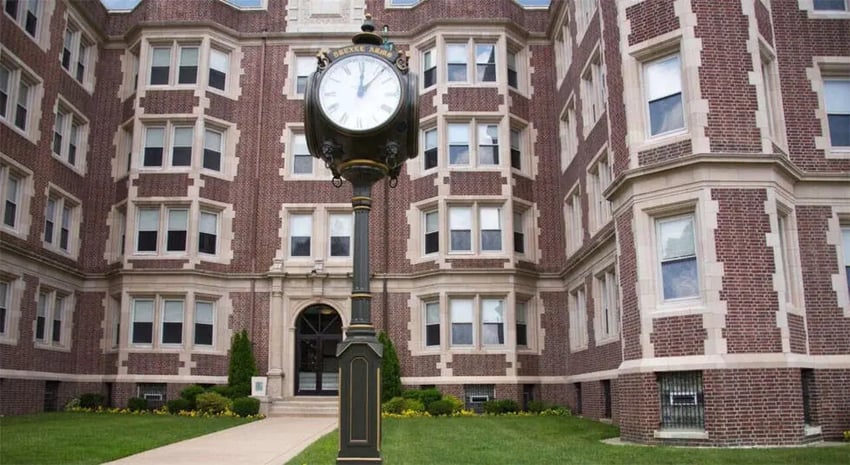Large clock and brick building exterior at The Legacy at Drexel Arms Apartments in Philadelphia Student Accommodation