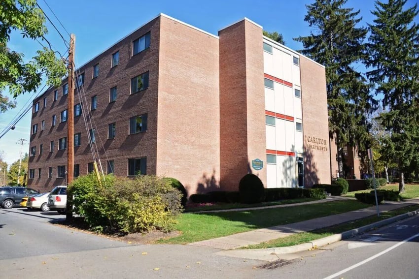 Carlton Apartments building with cars parked exterior at The Carlton in State College Student Accommodation
