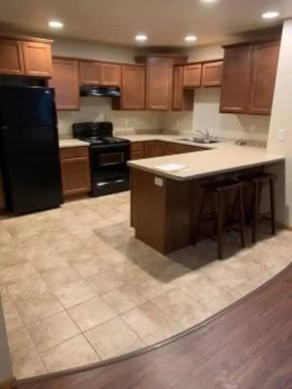 Black refrigerator stove cabinets island kitchen at Biondo Properties, LLC in La Crosse Student Accommodation