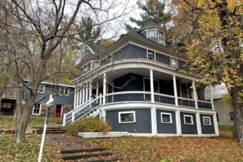 Large dark house with wraparound porch exterior at Copper Country Rentals in Houghton Student Accommodation
