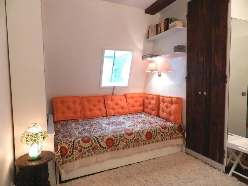 Bed with orange cushions dark wood wardrobe bedroom at Studio in Rue Dauphine, 75006 Paris, France in Paris Student Accommodation