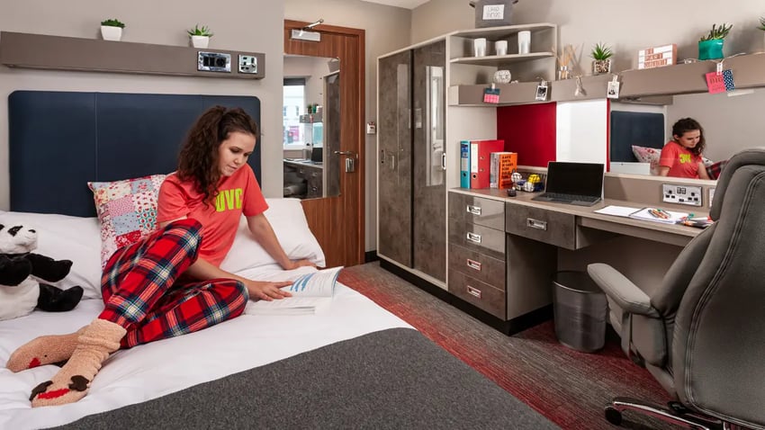 Woman on bed with desk and wardrobe Bedroom at Study Inn Talbot Street Nottingham in Nottingham Student Accommodation