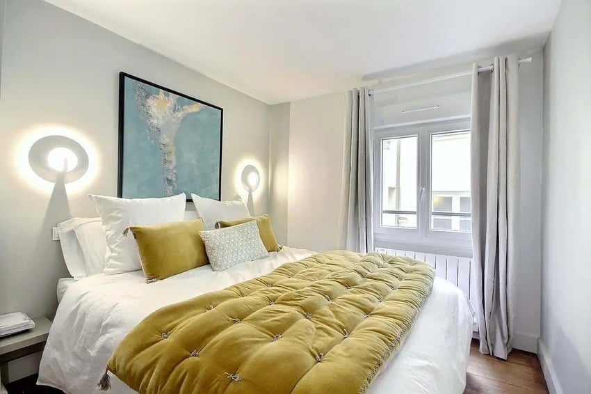 Bed with yellow accent pillows and art bedroom at Apartment 1 bedroom 60m² in Paris Student Accommodation