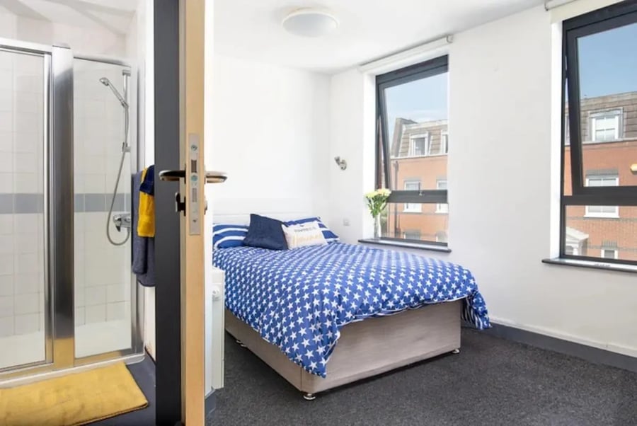 Shower stall and bed with blue star bedding Bedroom at Fulham Palace Studios in London Student Accommodation