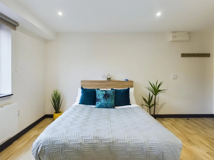 Bed pillows plants wood floor bedroom at Eden Square in Coventry Student Accommodation