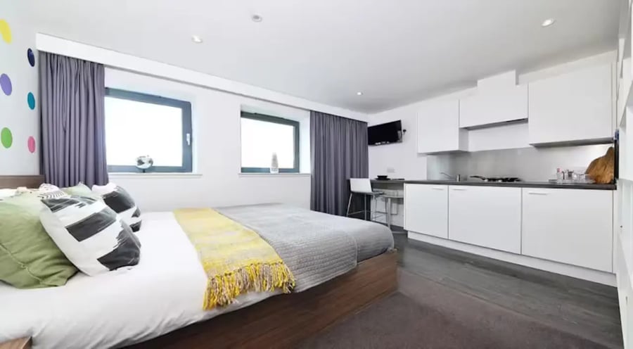 Bed kitchen area with white cabinets and TV studio apartment at Gallery Apartments in Glasgow Student Accommodation