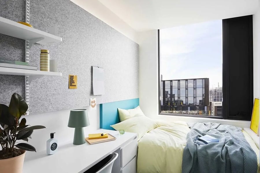 Bed desk plant and window view student bedroom at Scape Lincoln College in Melbourne Student Accommodation