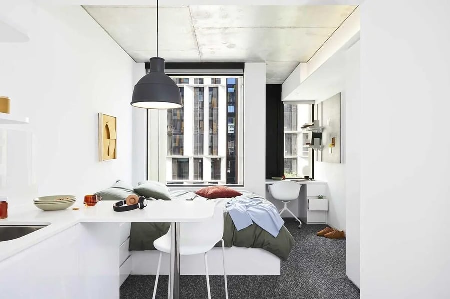 Bed desk table with kitchen and seating study area at Scape Lincoln College in Melbourne Student Accommodation