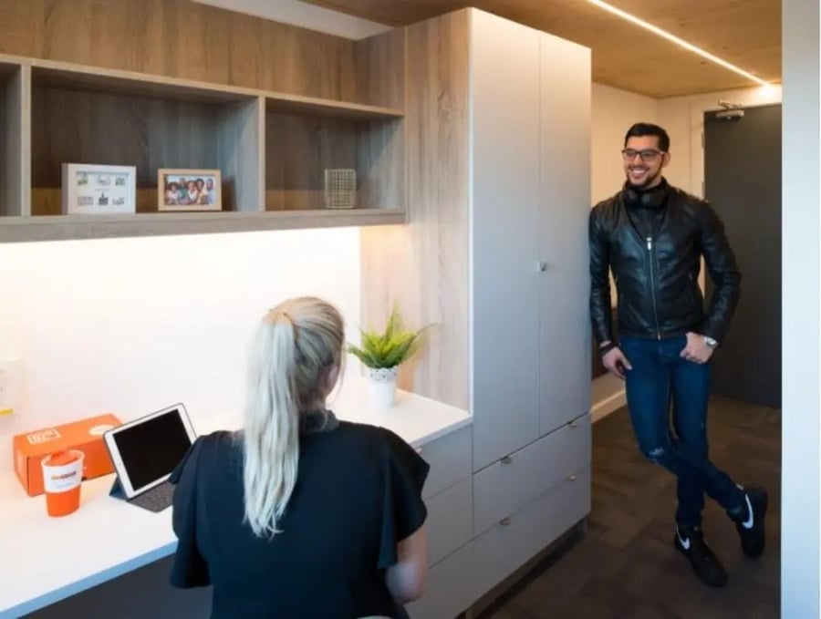 Desk with tablet and man by wardrobe bedroom at Gillows in Lancaster Student Accommodation