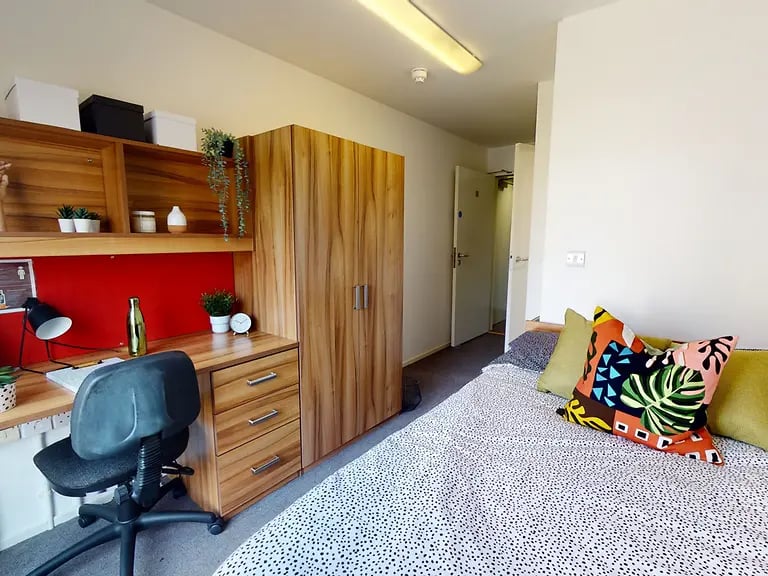Desk wardrobe and bed with cushions Bedroom at CB1-Cambridge in Cambridge Student Accommodation